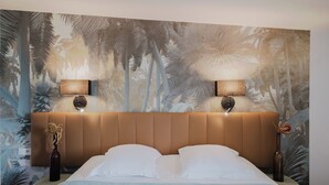 A bedroom with a large bed, two wall-mounted lamps, and a tropical-themed mural on the wall. - Hôtel Amaya (Ambares-et-Lagrave)