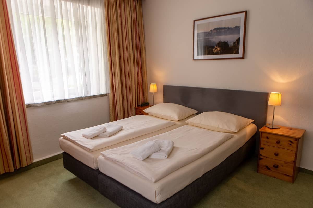 Una cama doble con dos almohadas y dos mesitas de noche con lámparas.