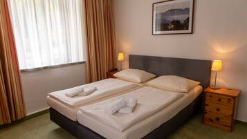 Una cama doble con dos almohadas y dos mesitas de noche con lámparas.