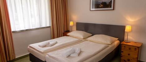 A double bed with two pillows and two bedside tables with lamps.