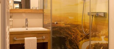 A modern bathroom with a glass-enclosed shower, a sink with a wooden vanity, and a large mirror.