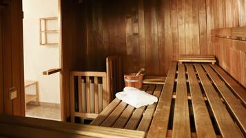 Una sala de sauna con bancos de madera, una silla de madera y un balde.