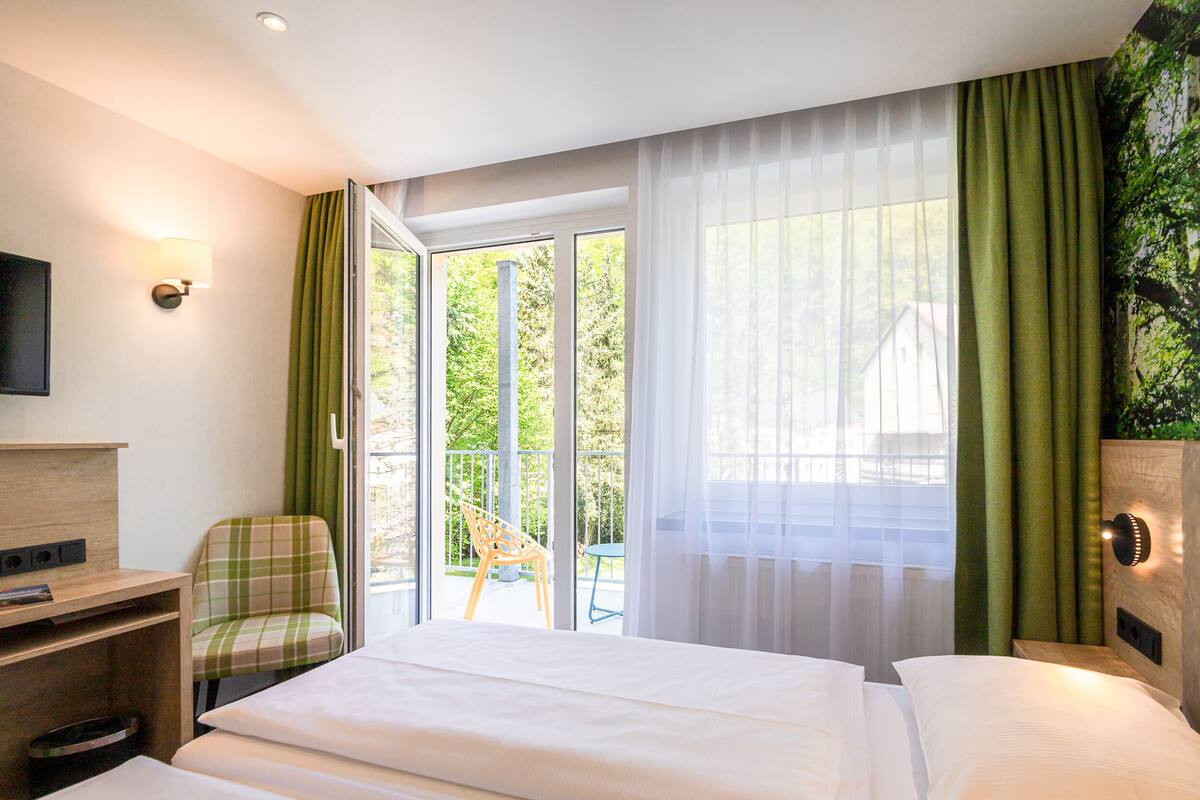 Una habitación de hotel con cama, una silla, un escritorio y televisor.