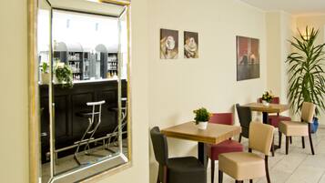 A dining area with tables and chairs, a large mirror, and artwork on the walls.