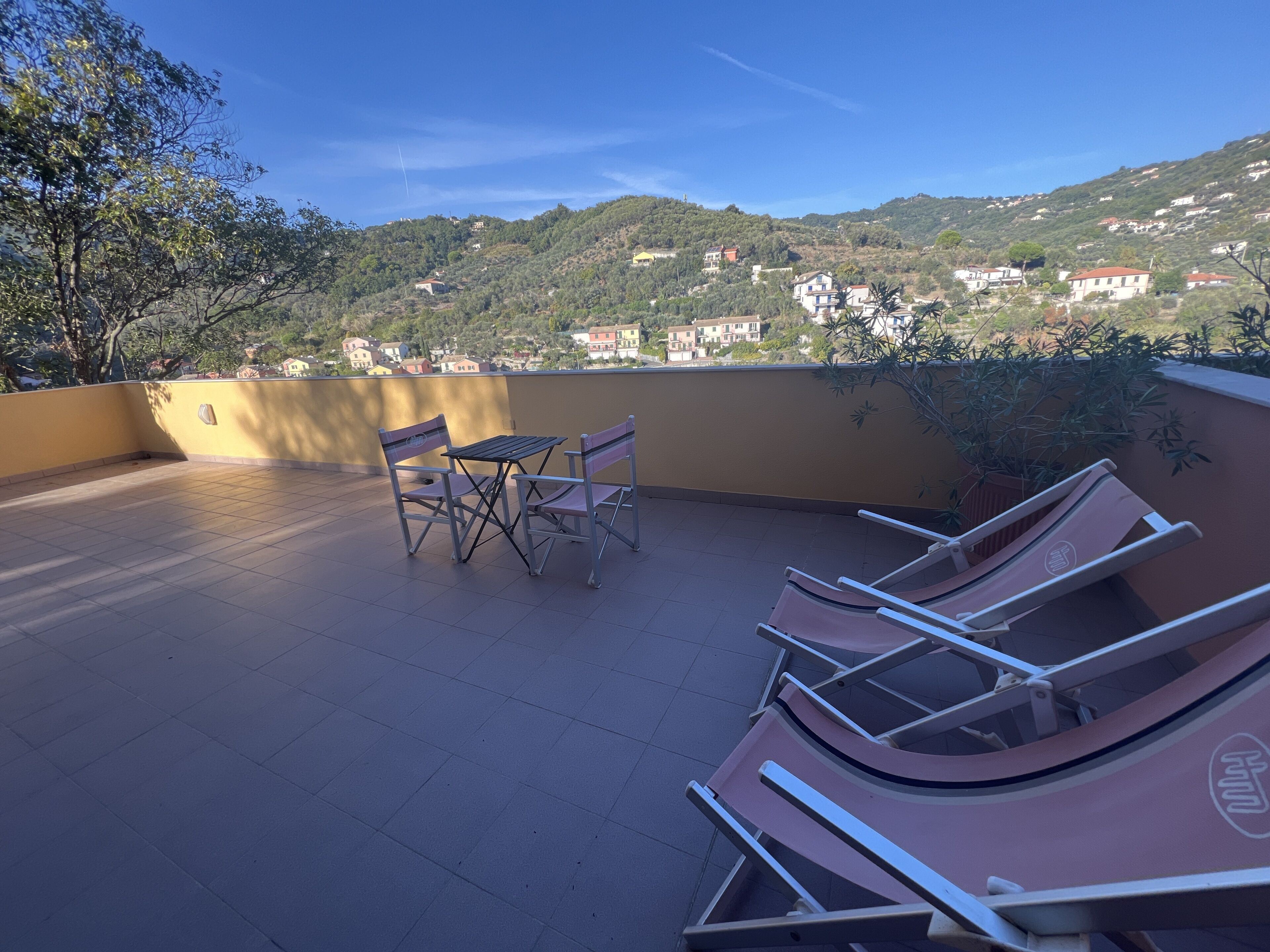 Una terraza con mesa y sillas, con vistas a una colina con edificios.