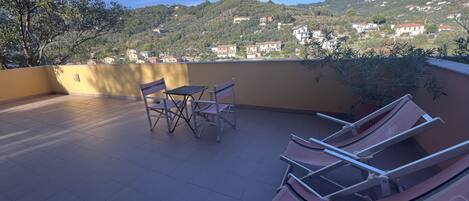 Una terraza con mesa y sillas, con vistas a una colina con edificios.