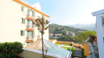 A building with a glass conservatory, a balcony, and a view of a hilly landscape.