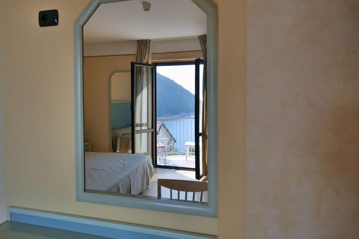 A bedroom with a bed, a window, and a view of a balcony and mountains.