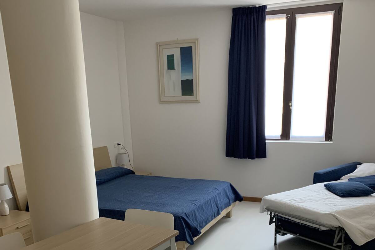 A bedroom with two beds, a desk, and a chair.