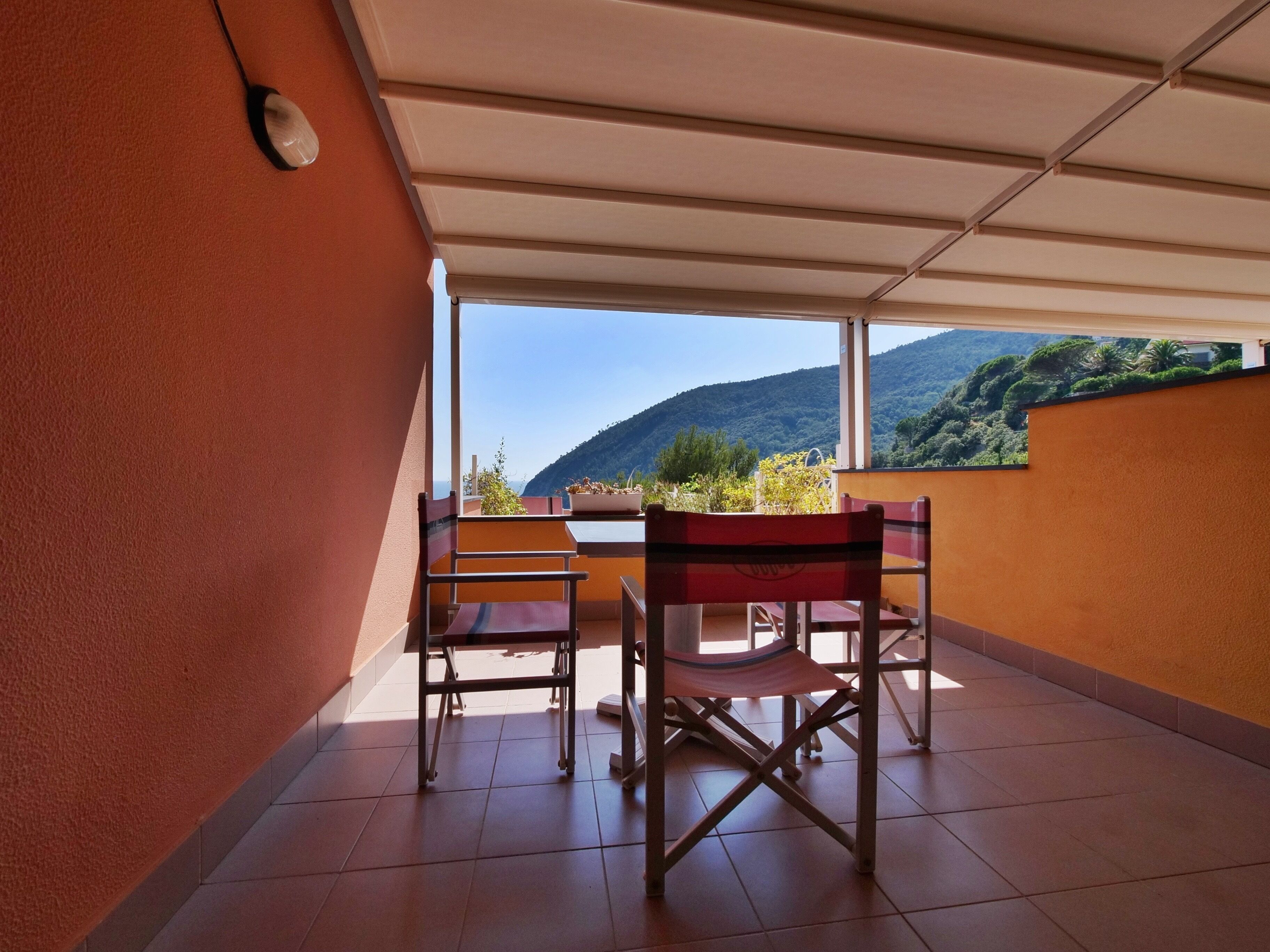 A balcony with a table and chairs, a view of a mountain, and a clear sky.