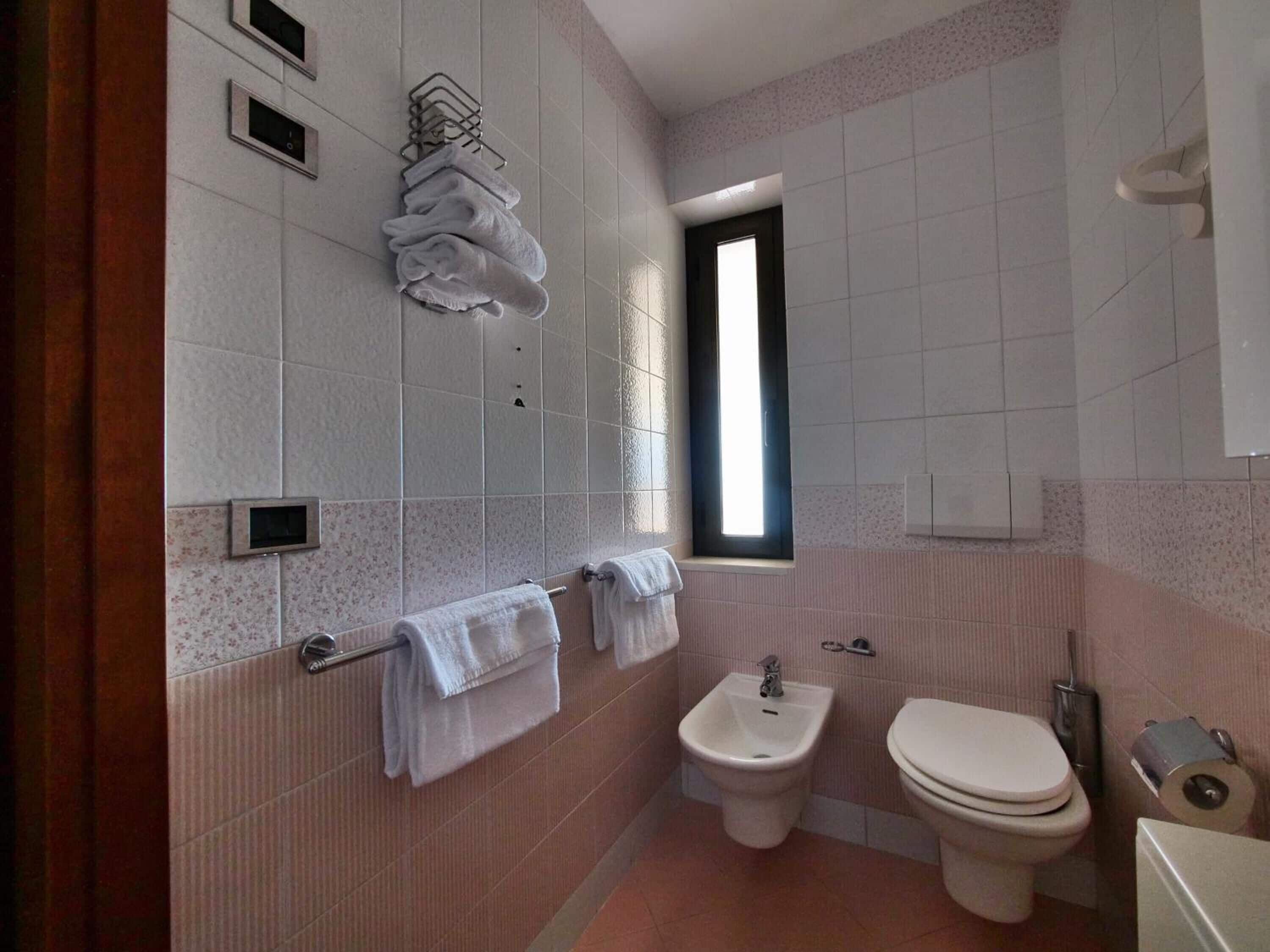 Un baño pequeño con inodoro, bidé y toallero.
