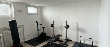 Un gimnasio con saco de boxeo, banco de pesas y equipo de ejercicio.