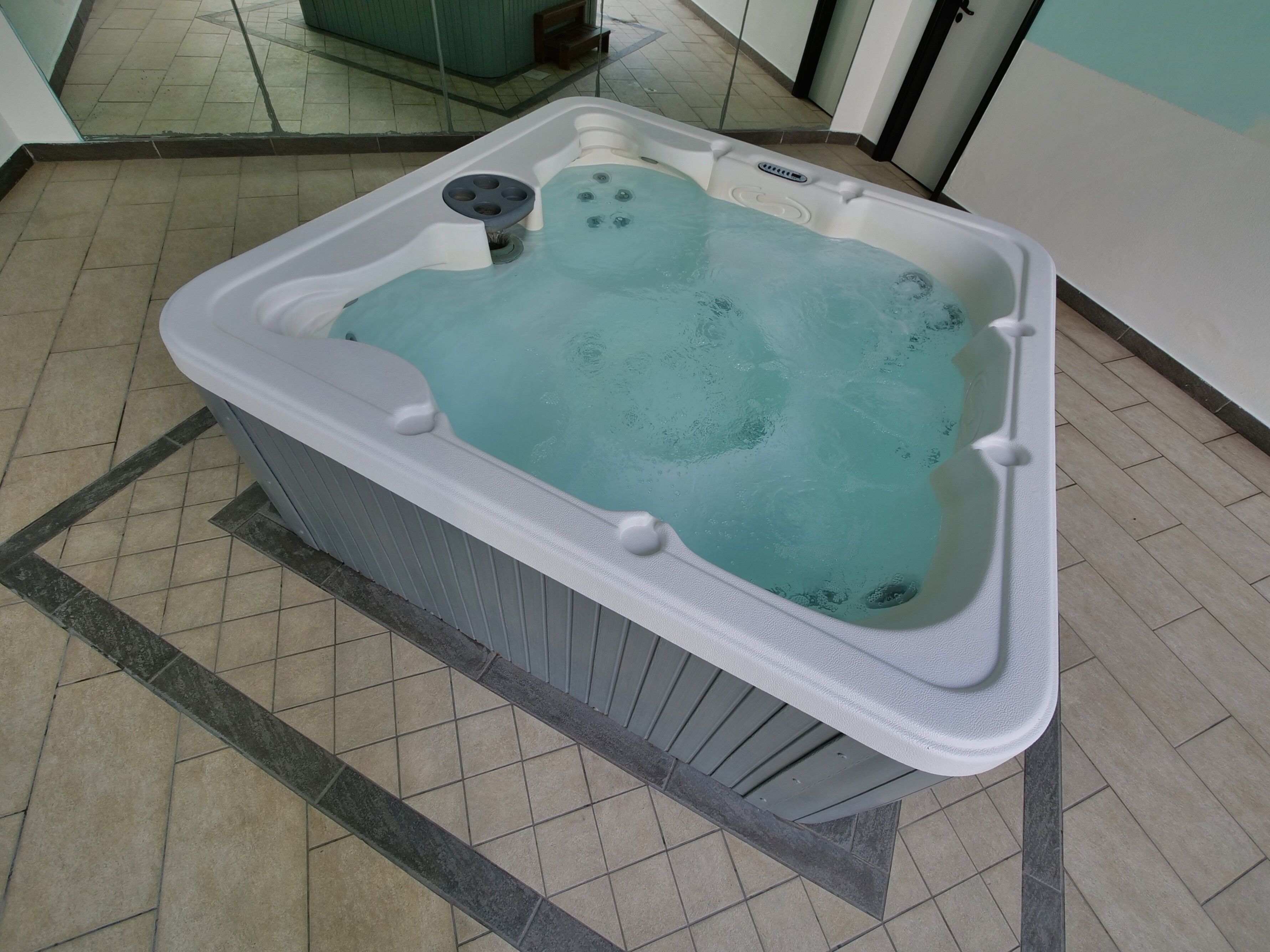 A hot tub with a control panel, a foot pedal, and a drain.