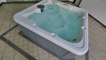 A hot tub with a control panel, a foot pedal, and a drain.