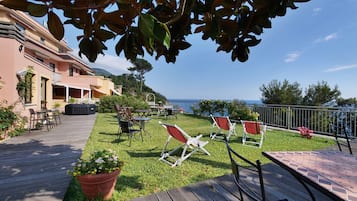 Une terrasse avec des places assises à l’extérieur, une vue sur la mer et un bâtiment doté d’un balcon.