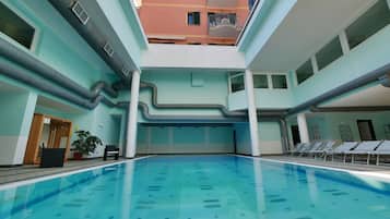 Une piscine dont le fond est carrelé, entourée de murs percés de fenêtres et dotée d’un balcon.