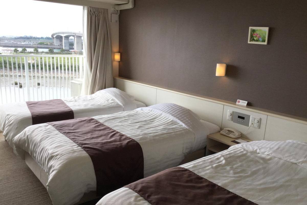 A hotel room with two beds, a view of a bridge, and a small bedside table with a phone.