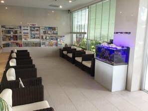 A reception area with a fish tank, seating, and a wall of magazines. - Hotel GranView Garden Okinawa (Tomigusuku)