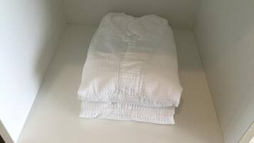 A neatly folded white towel on a white shelf in a room with plain walls.