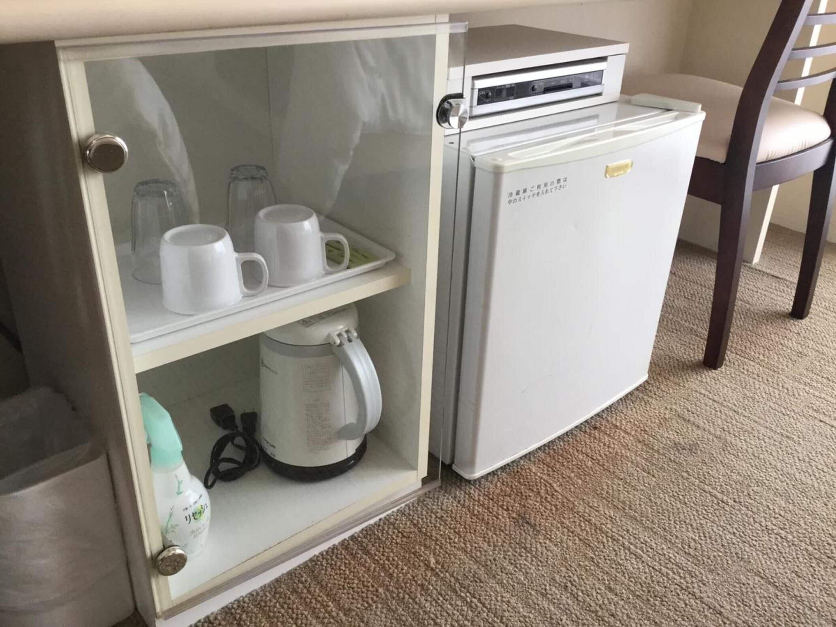 A compact kitchenette with a coffee maker, a kettle, and a small refrigerator.