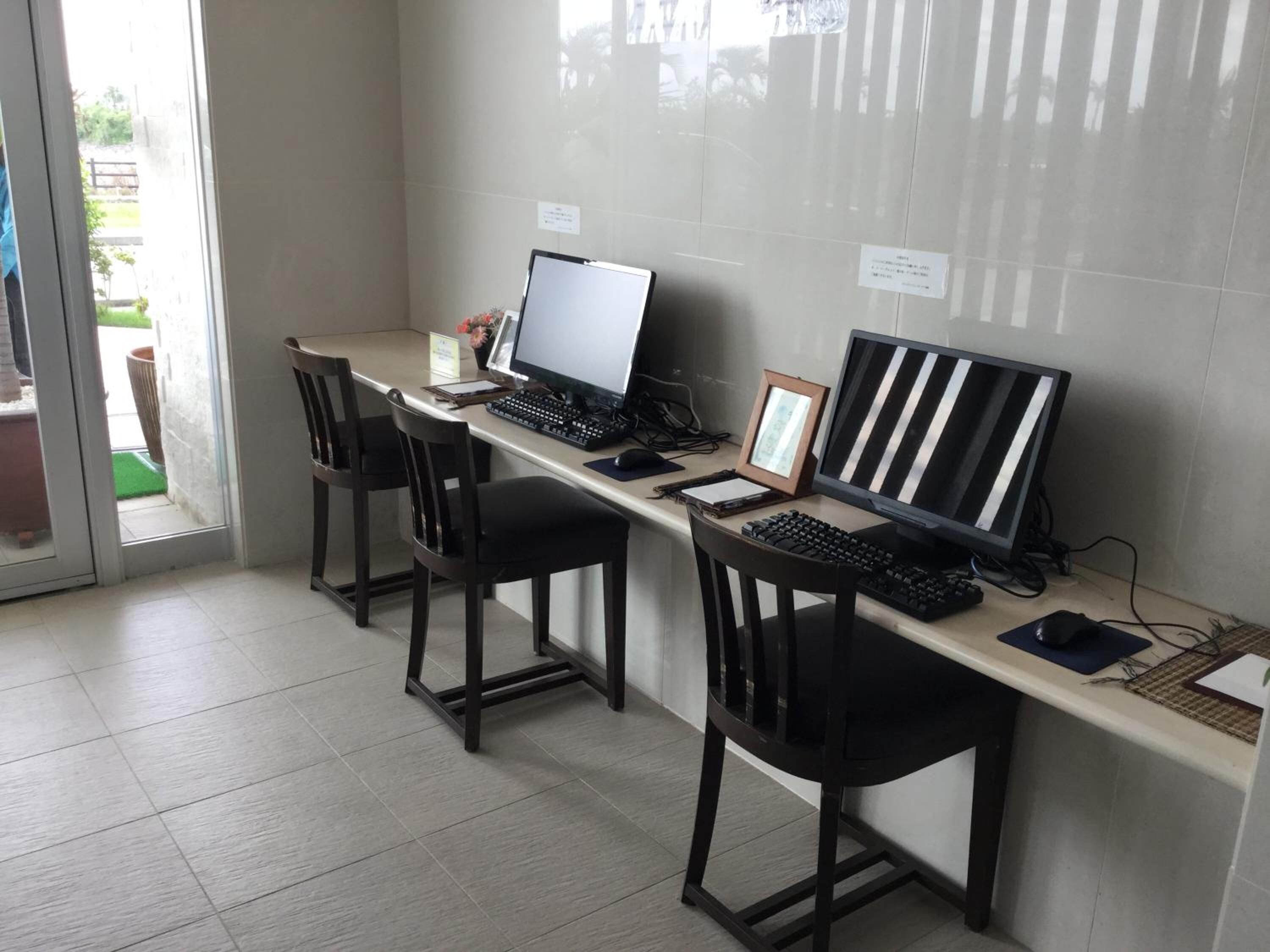 A workspace with three desks, each equipped with a computer, keyboard, and chair.