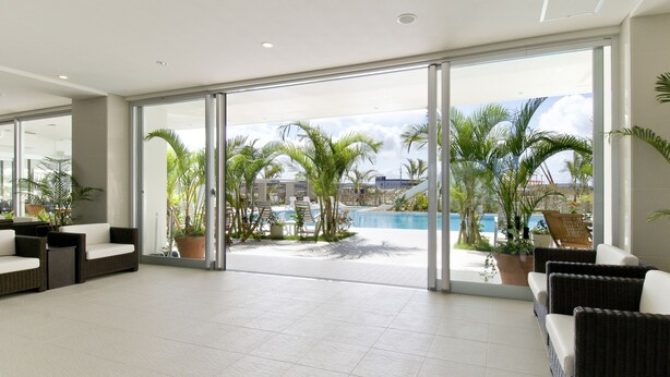A spacious lobby with a pool view, modern furniture, and large sliding glass doors. - Hotel GranView Garden Okinawa (Tomigusuku)