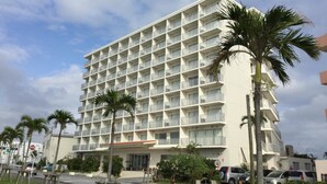 A multi-story hotel with a grid of balconies, surrounded by palm trees and a clear sky. - Hotel GranView Garden Okinawa (Tomigusuku)