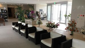 A reception area with wicker chairs, a reception desk, and floral arrangements. - Hotel GranView Garden Okinawa (Tomigusuku)