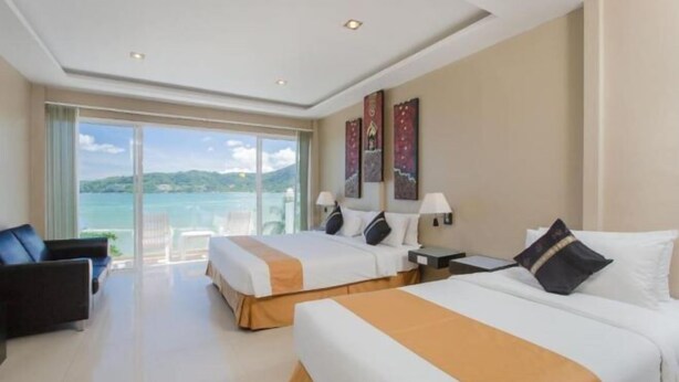 Habitación de hotel con dos camas, un sofá, un escritorio y vista al mar.