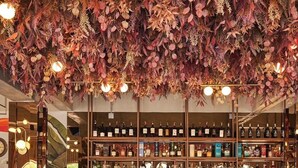 A bar area with a marble counter, three green bar stools, and a ceiling decorated with autumn leaves and lights.