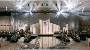A stage with a white backdrop, two white unicorn statues, and a central logo.