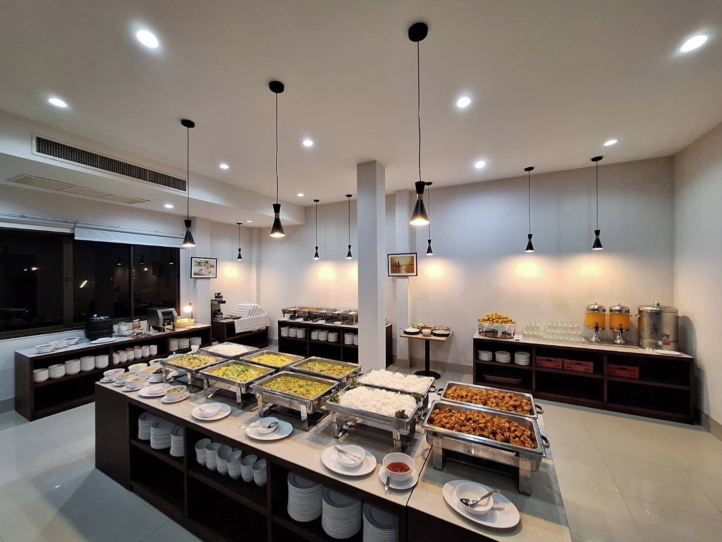 Zona de buffet amb diverses estacions de menjar, incloent plats de rice, verdures i altres propostes culinàries.