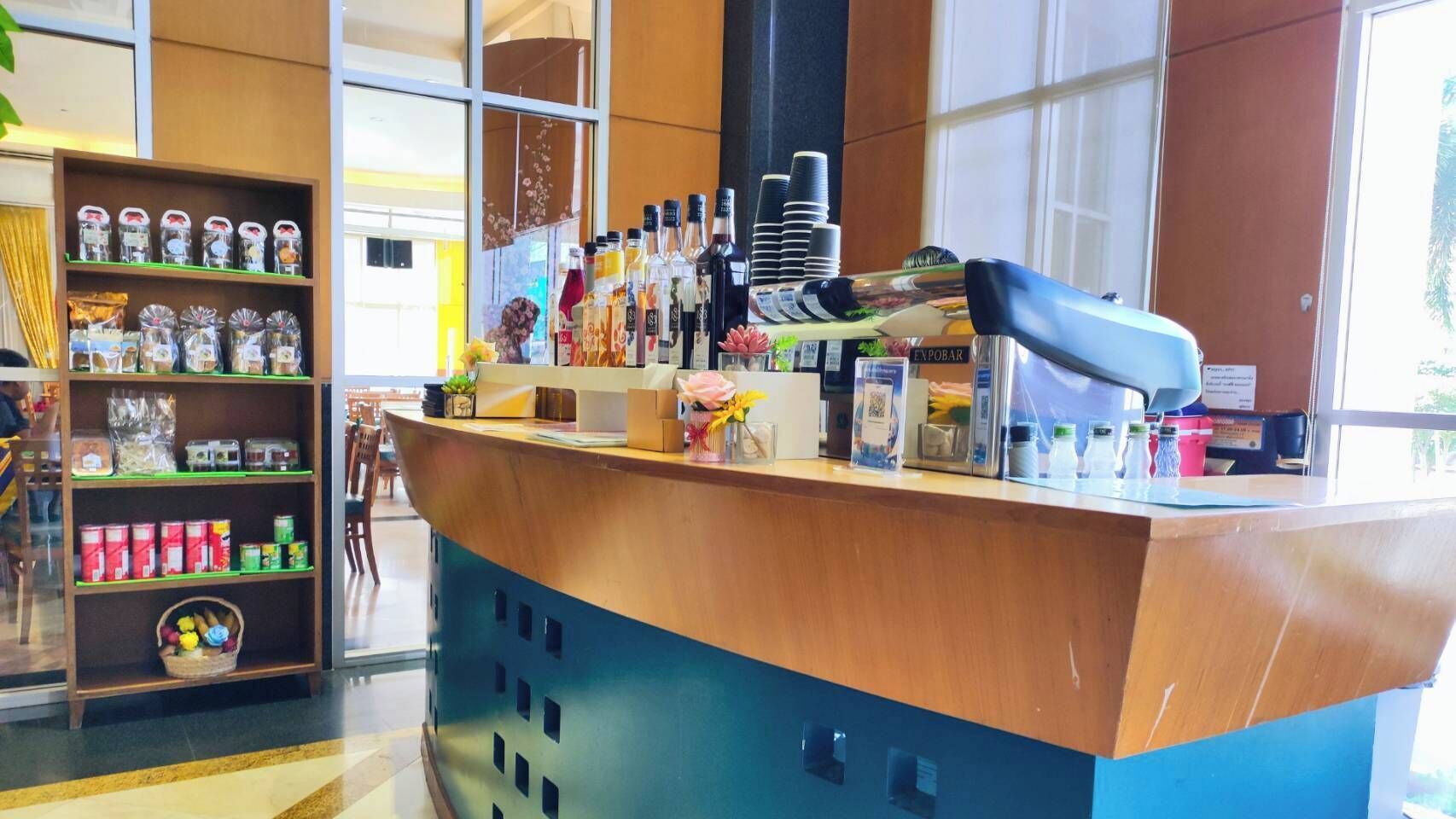 A bar area with a counter, shelves with snacks, and a variety of bottles.