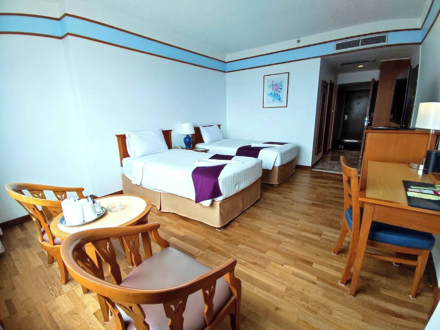 Een hotelkamer met twee bedden, een bureau, een stoel en een klein tafeltje.