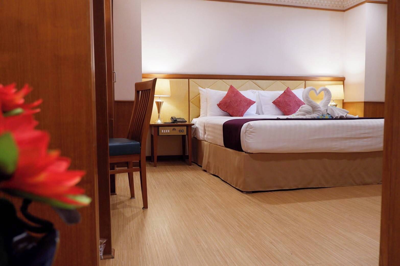 A hotel room with a bed, a chair, a nightstand, and a lamp.