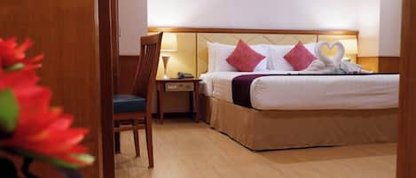 A hotel room with a bed, a chair, a nightstand, and a lamp.