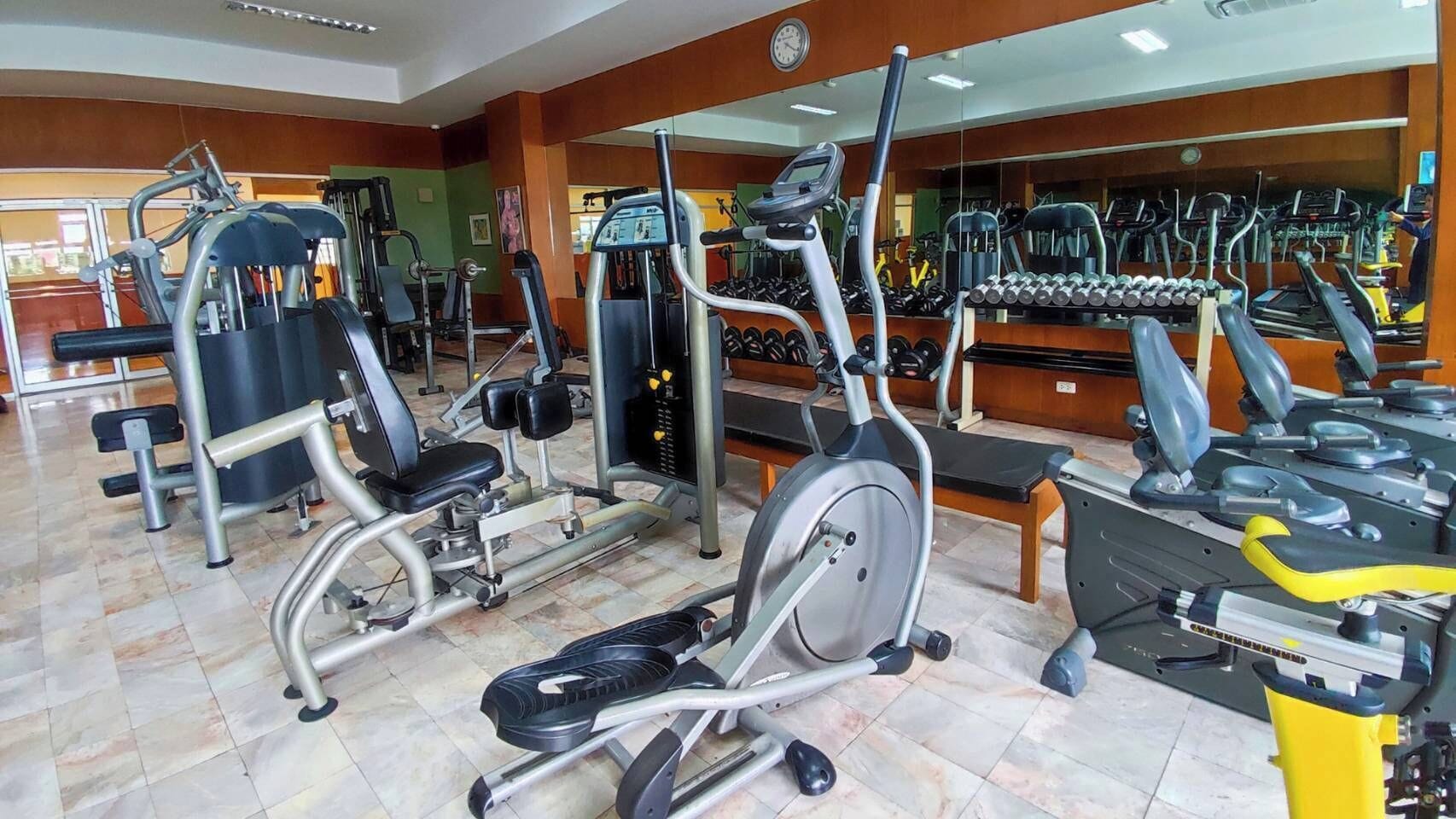 A gym with various exercise equipment including treadmills, elliptical machines, and weight machines.
