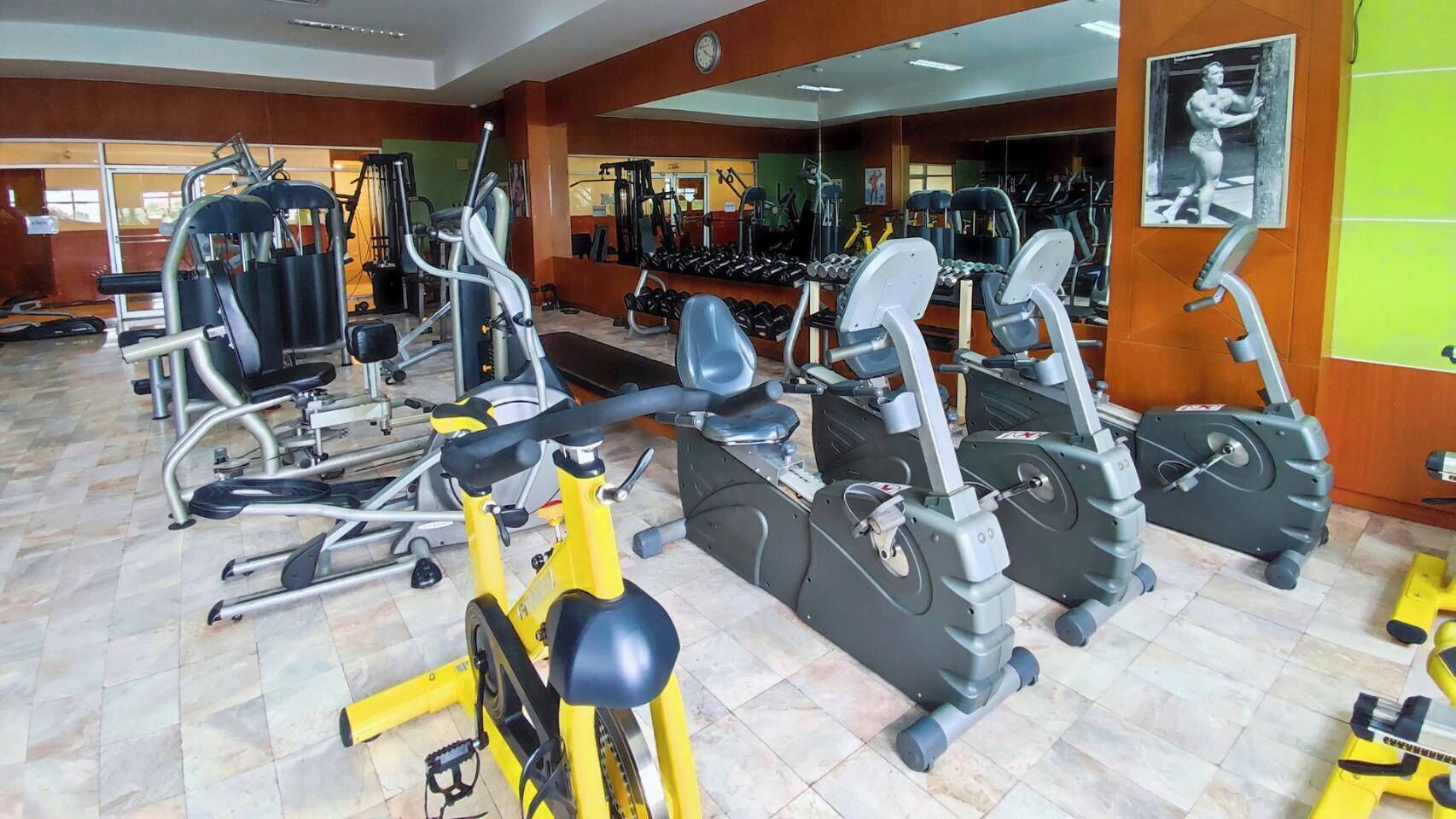 Une salle de sport équipée de divers appareils d’exercice, notamment des tapis de course, des vélos d’appartement et des appareils de musculation.