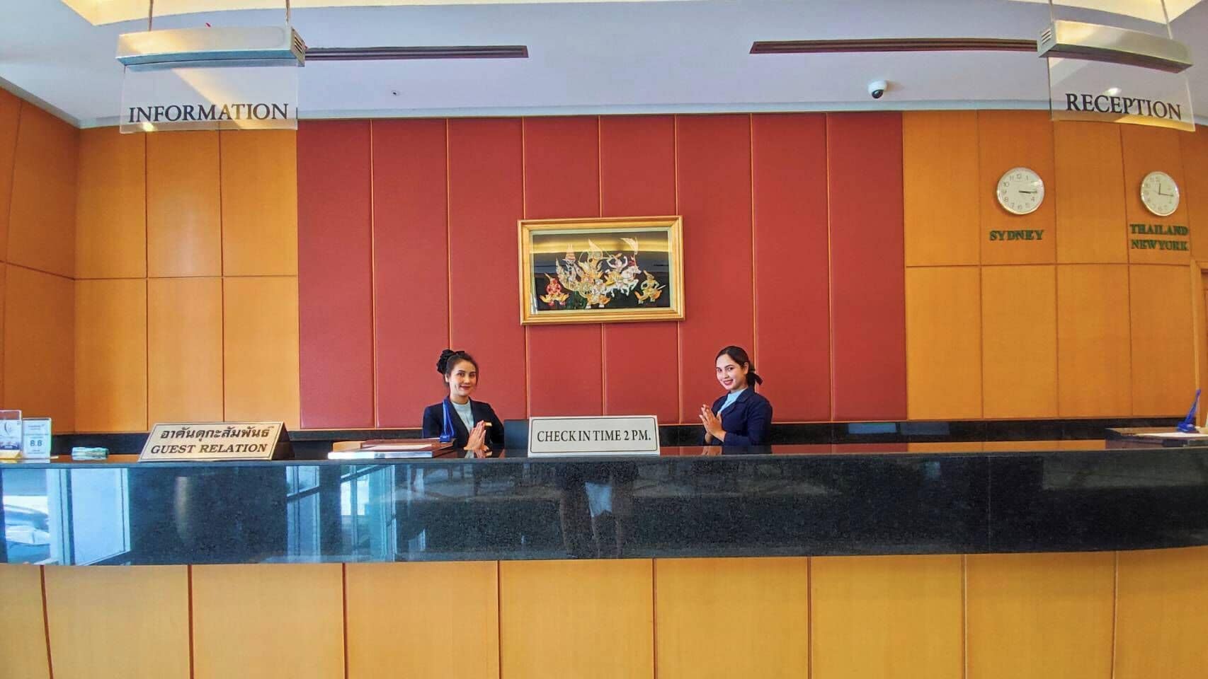 A reception desk with two staff members, a clock, and signs indicating 'Information' and 'Reception' areas.