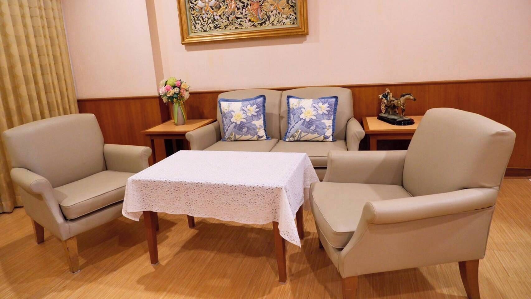 A room with a sofa set, a table with a lace tablecloth, and a decorative vase with flowers.
