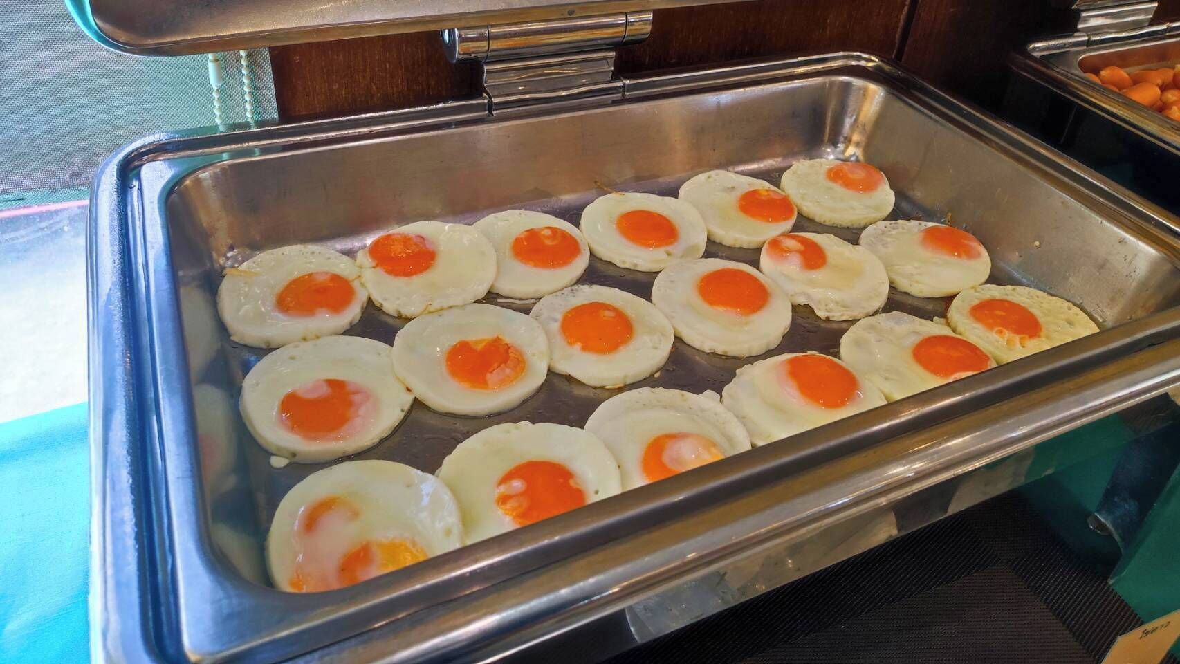 A buffet tray with several fried eggs.