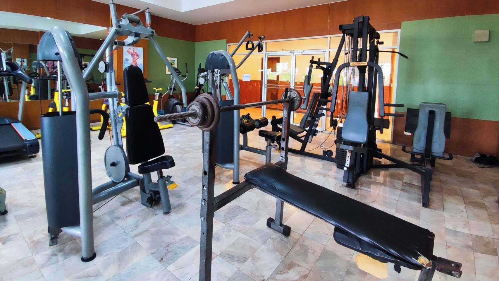 A gym with various exercise equipment, including weight machines and a bench.