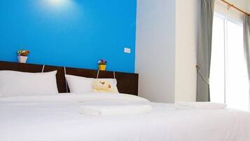 Un lit bien fait, avec du linge de lit blanc, une tête de lit en bois et un mur d’accent bleu.