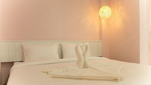 Una habitación de hotel con una cama bien hecha, un cabecero y una lámpara fijada a la pared.