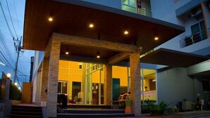 Un edificio moderno con vestíbulo cubierto, ventanas amplias y un balcón.
