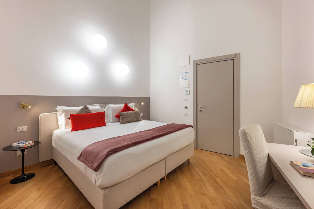 Una habitación de hotel moderna con cama, mesita de noche, escritorio y silla.