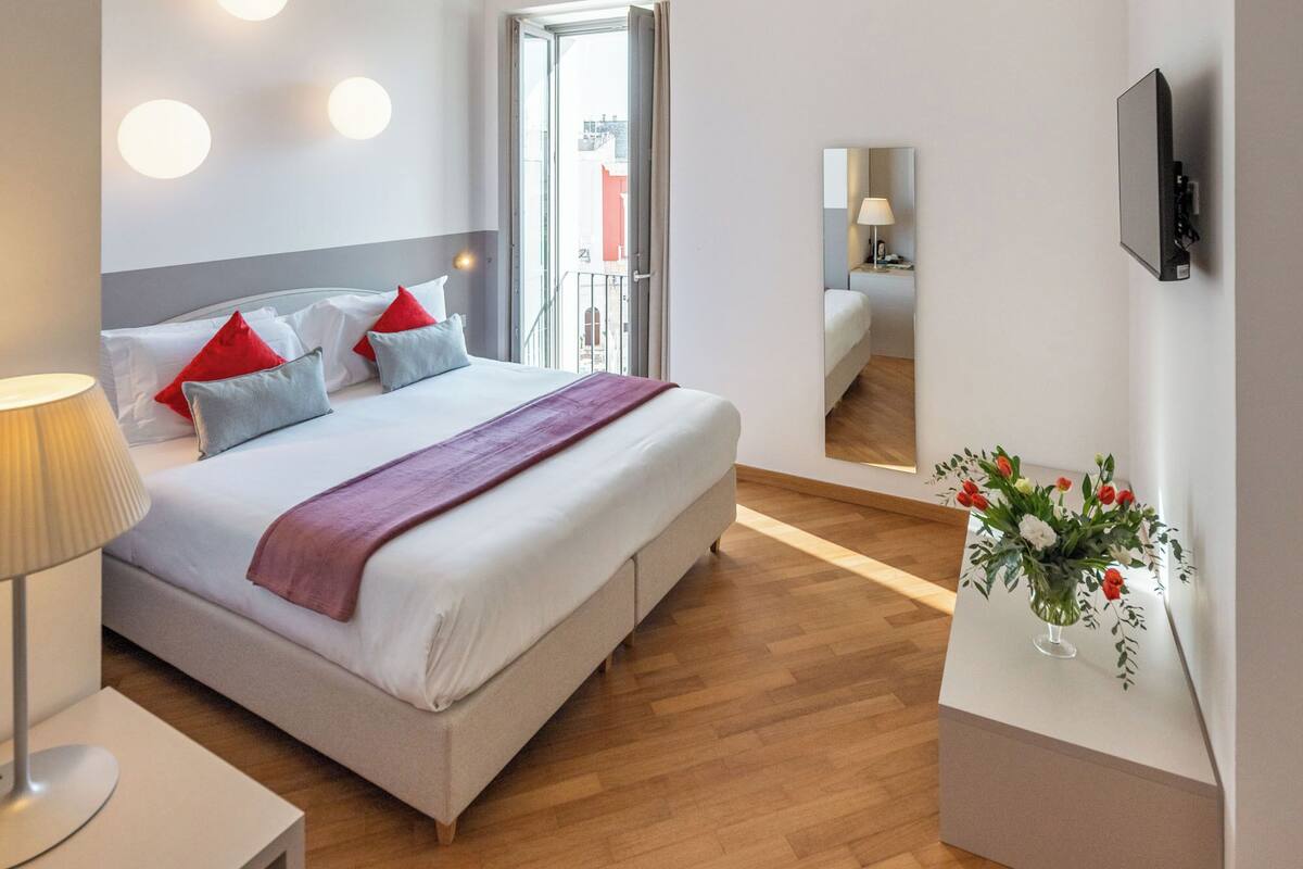 Una habitación de hotel moderna con una cama grande, una mesita de noche y un espejo.