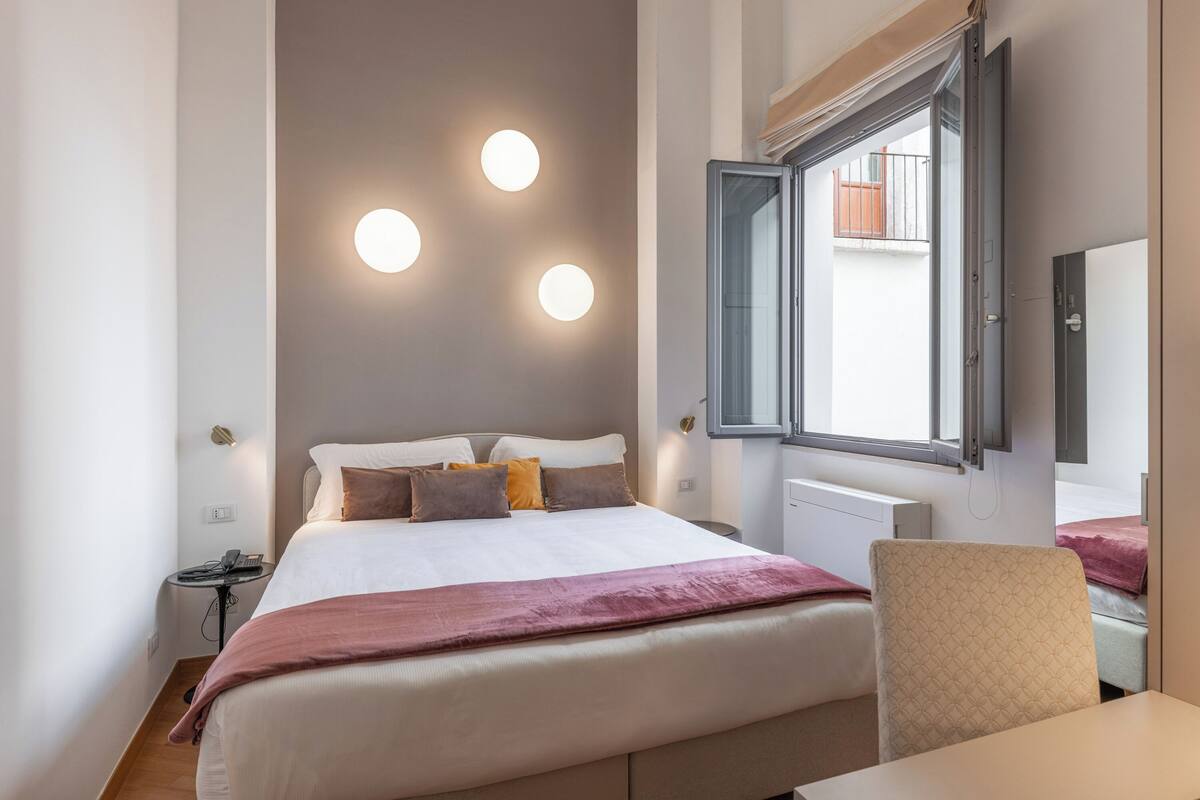 Un dormitorio ordenado con cama, mesita de noche y una silla.