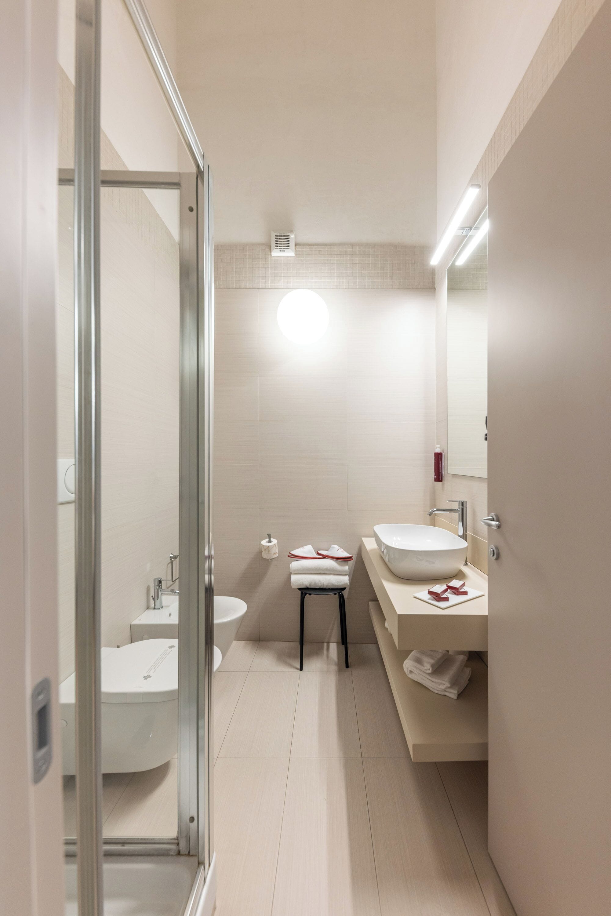 Een moderne badkamer met een glazen douchecabine, een witte wasbak en een spiegel.