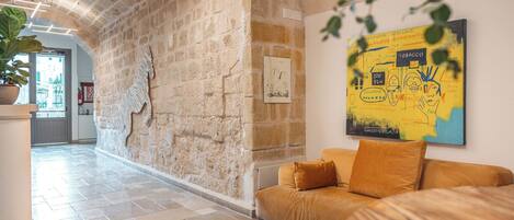 A hallway with stone walls, a sofa, and a map on the wall.